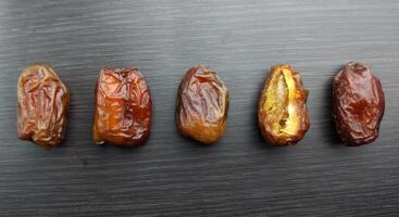 dried dates on a black background. Top view, flat lay photo