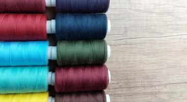 Spools of multicolored thread on wooden background with copy space photo