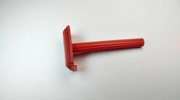 Red plastic shaving razor on a white background, closeup of photo