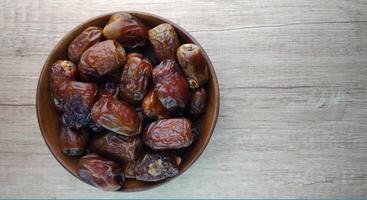 Dates fruit in a wooden bowl on a wooden background. Top view. photo