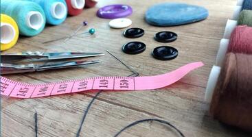 Sewing accessories on a wooden background Sewing accessories thread scissors pins tape measure. photo