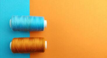 roll of blue and orange thread on blue and orange background, top view, contrast concept photo