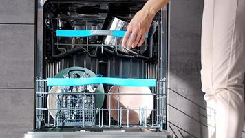 Close up view of woman putting dirty ceramic dish in the dishwasher. Household and helpful technology concept. High quality 4k footage video