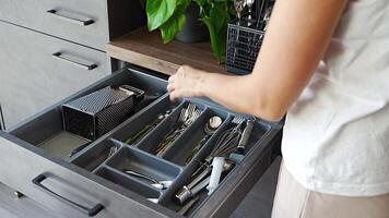 Woman housewife hands tidying up cutlery after dishwasher machine. Woman neatly assembling fork, spoon, knife accessories for storage organization . High quality 4k footage video