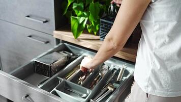 Housewife hands tidying up cutlery after dishwasher machine. Focus on woman neatly assembling fork, spoon, knife accessories for storage organization . High quality 4k footage video