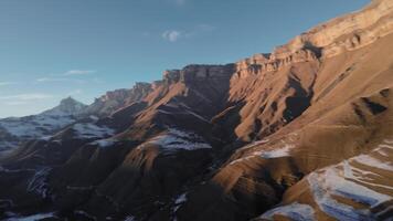 aereo Visualizza di fpv volante dietro a il uccello di preda avvoltoio. lento movimento. chasing un' selvaggio uccello nel il aria al di sopra di il montagne a tramonto. montagne coperto con neve video