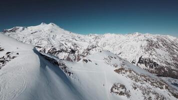 aérien vue de paysage de neigeux Montagne intervalle dans Caucase, en dessous de bleu ciel, hiver métrage de drone 4k video