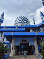 The blue dome of the mosque has a background of sky and clouds photo