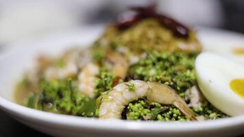 picante neem árbol flor con langostinos ensalada en un blanco plato en un de madera mesa. video