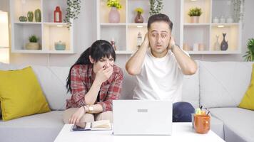 The couple is upset by what they see on the laptop. video