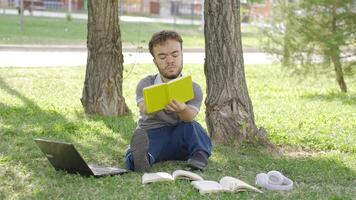 Universität Zwerg Schüler studieren draußen im das Park ist unzufrieden. video