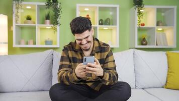 a jovem homem mensagens de texto em a telefone risos Fora alto. video