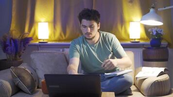 masculino estudiante estudiando a noche en ordenador portátil ligero. video