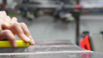 Hand hold brush and brushing wax on snowboard close up. Snowboard preparation in ski repair shop video