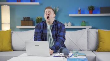 Home office worker man yawns and relaxes at the camera. video