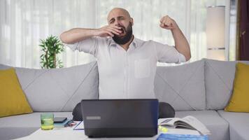 Home office worker man yawns and relaxes at the camera. video