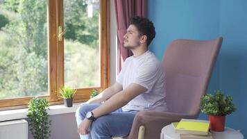 el hombre en frente de el ventana, tomando un profundo aliento y clausura su ojos. video