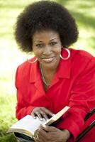 Middle-aged Black woman outdoor reading Bible smile photo