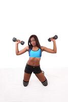 Young black woman on knees with dumbbells photo