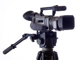 Black Video camera mounted on tripod against white photo