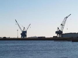 Boston, MA, 2008 - Two Cranes In Near Silhouette With Bay In Foreground photo