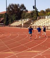 palo Alto, California, 2006 - Tres joven muchachas corriendo en pista corriendo competencia foto