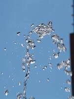 agua gotas desde fuente yendo arriba y que cae en contra azul cielo foto