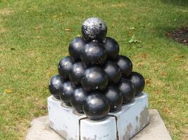 Boston, MA, 2008 - Stack Of Black Round Cannon Balls On Cement Platform Green Grass photo