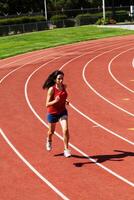 joven Hispano adolescente mujer corriendo en rojo pista foto