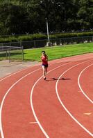 joven Hispano adolescente mujer corriendo en pista hacia cámara foto