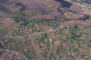 Aerial Shot Of Agricultural Fields And Small Village Along Road photo