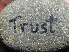 Trust written on small rock in natural light photo