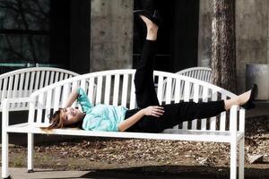 Smiling Asian American Woman Reclining On Bench Outdoors photo