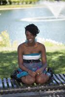 joven atractivo negro mujer al aire libre sentado en banco foto