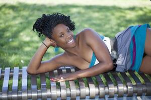 atractivo joven negro mujer reclinable en banco foto