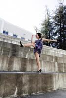 joven asiático americano mujer pateando pierna arriba en vestir al aire libre foto