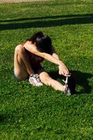 Young Hispanic Teen Girl Streching On Green Grass Red Top photo