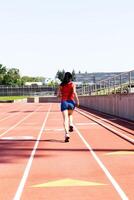 Hispano adolescente niña corriendo en pista desde espalda azul pantalones cortos foto