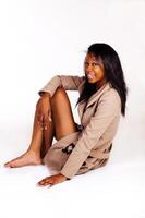 sonriente africano americano mujer sentado en chaqueta en piso foto