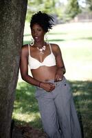 Attractive black woman outdoors slacks and bra photo