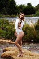 caucásico adolescente mujer en pie en blanco leotardos a río foto