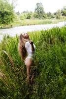 adolescente caucásico mujer al aire libre en pie en alto verde césped foto