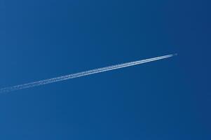 Jet With Ice Trail Streaming Behind In Blue Sky photo