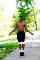 africano americano hombre al aire libre saltando cuerda en parque foto