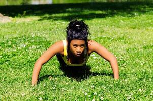 African American Woman Doing Push-up Outdoors In Grass photo