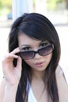 Portrait Asian American woman peeking over sun glasses photo