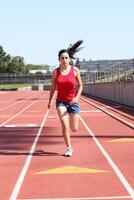 Young hispanic teen girl running on track photo