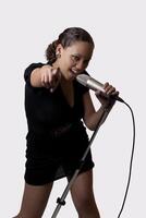 Young mixed ethnic woman with mic pointing photo