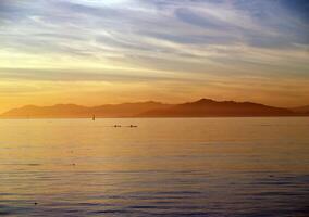 silhouette of kayaks on water with clouds photo