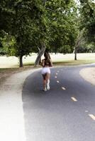 Teen Woman Running On Bike Trail From Back photo